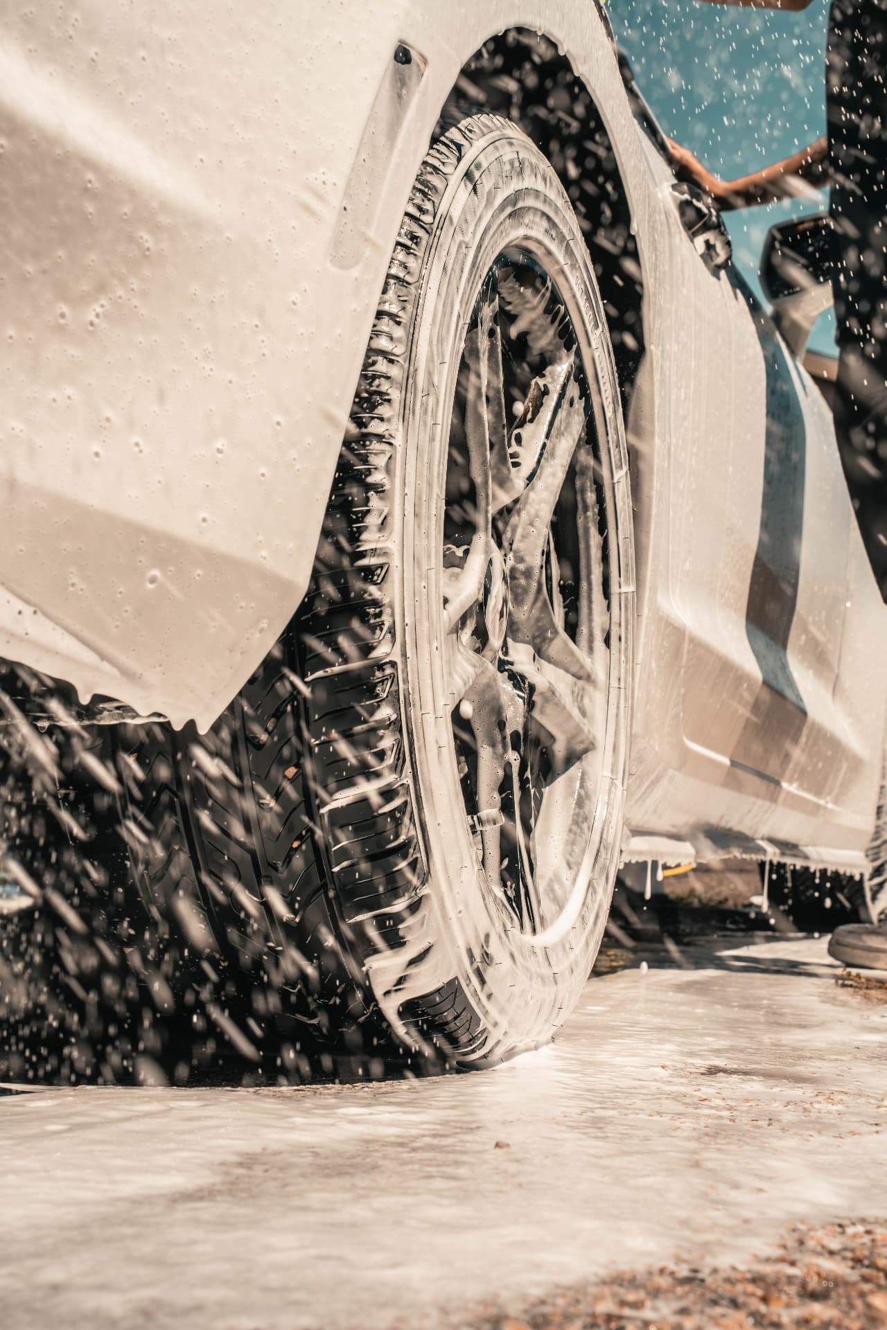Suds running off a wheel and rocker panel during a hand wash