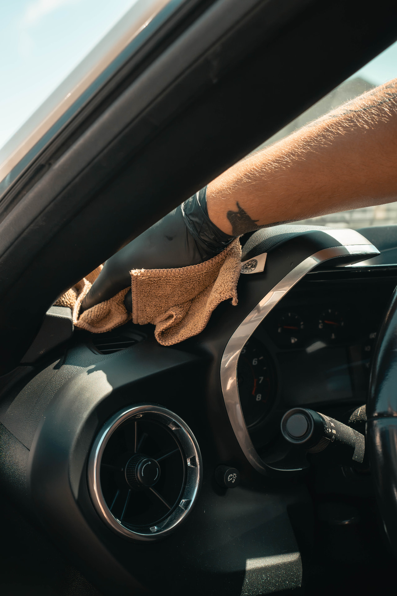 Gloved hand wiping down a dashboard with a microfiber towel