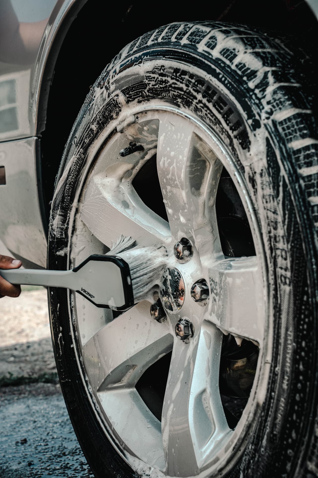 Foaming and scrubbing a wheel with a detailing brush