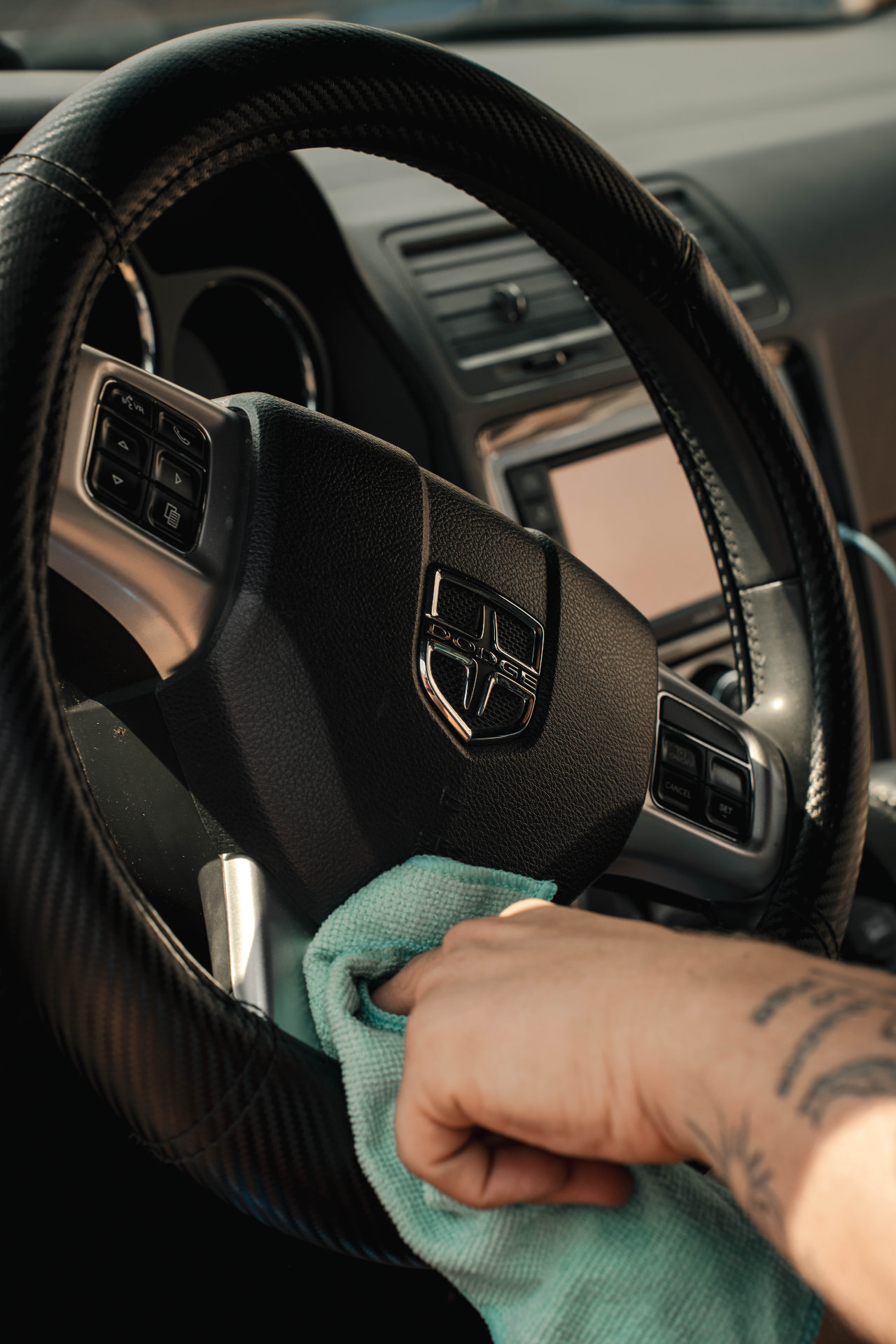 Wiping down a Dodge steering wheel and dash during an interior detail